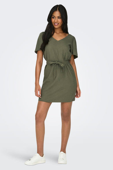 Groene jurk met korte mouwen van JDY, met een tailleband en gedragen met witte sneakers.
