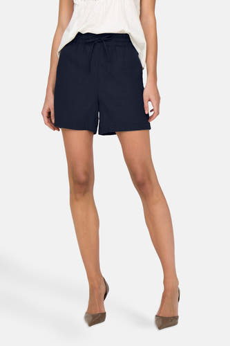 Short bleu marine de JDY, vu de de l'arrière, associé à une chemise blanche avec des détails bordés et des talons hauts.