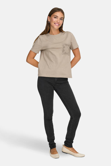 T-shirt beige à manches courtes de JDY, avec un détail en tricot, associé à des jeans noirs et des ballerines crème.