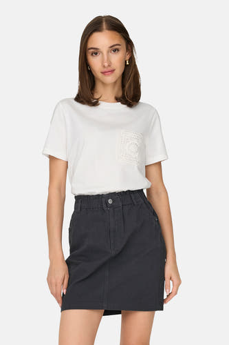 T-shirt blanc à manches courtes de JDY, avec un détail de poche en crochet, combiné avec un jean foncé et un sac beige.
