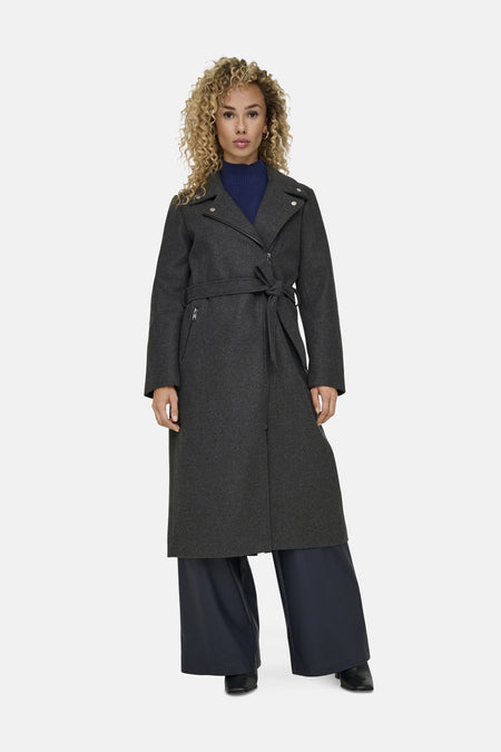Manteau long gris d'ONLY, avec ceinture et porté sur une veste bleue et un pantalon large.