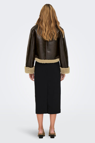 Manteau court brun d'ONLY, avec collet et porté sur une jupe noire en cuir et des chaussures.