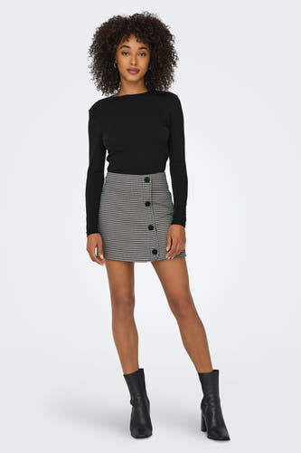 T-shirt noir à manches longues de ONLY, porté avec une mini-jupe évasée et des bottes noires.