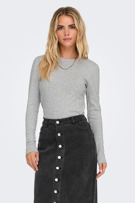 T-shirt gris à manches longues de ONLY, avec un col rond et porté avec une jupe noire à boutons.