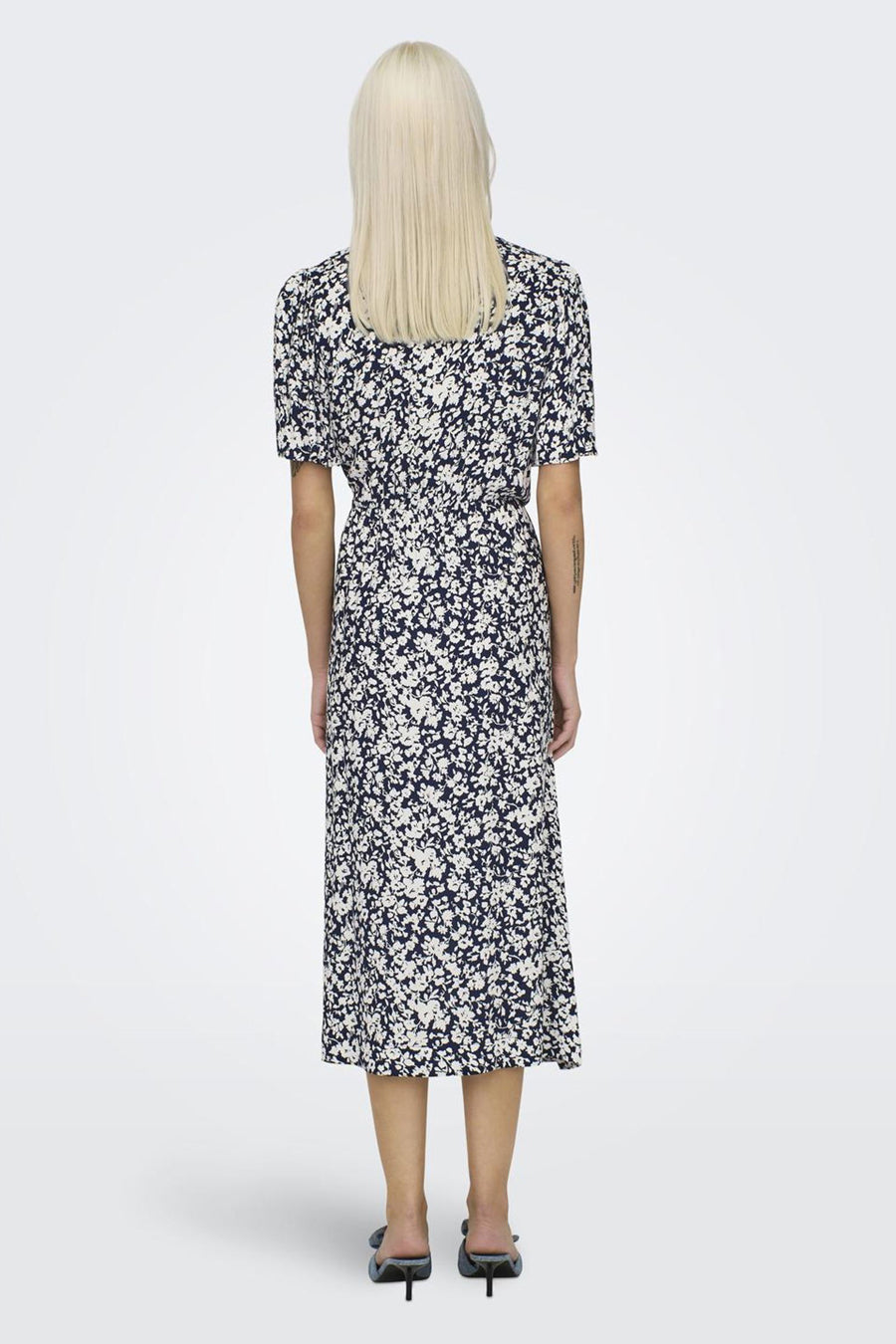 Achterkant van een vrouw in een blauwe bloemenjurk.