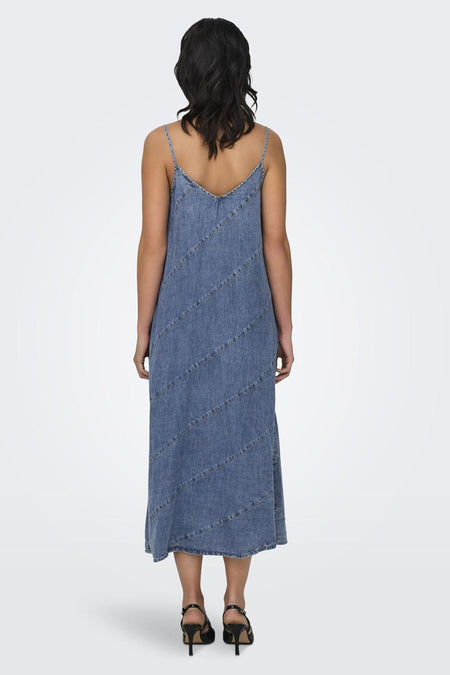Robe sans manches en denim bleu moyen ONLY® avec coutures diagonales, dos, portée avec des sandales noires.