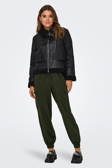 Zwarte korte jas van ONLY, met imitatieleer afwerking en groene cargo broek en zwarte schoenen.
