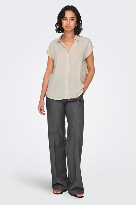 Pantalon gris de ONLY, associé à une blouse beige et des sandales.