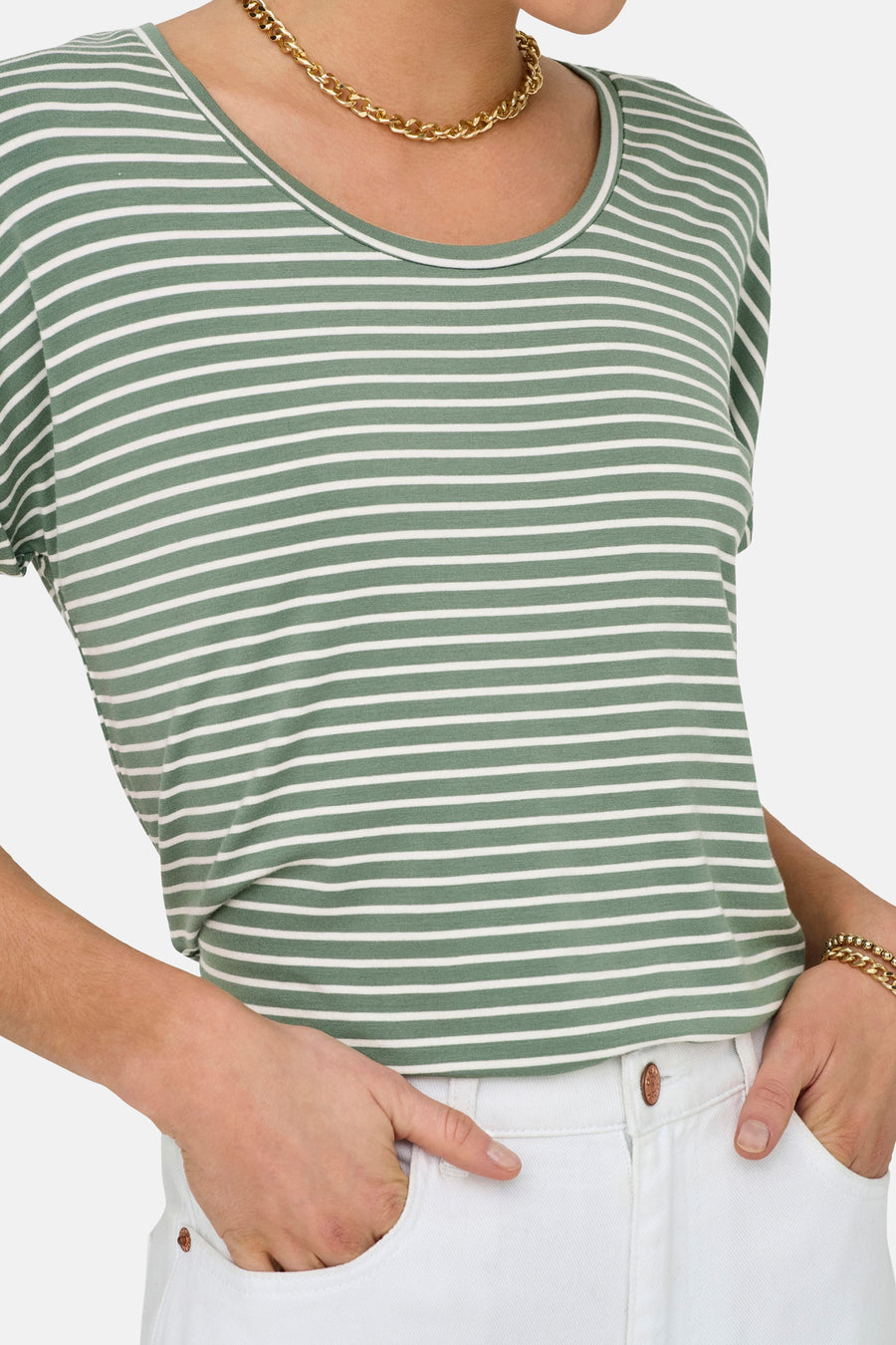 T-shirt vert à manches courtes de JDY, avec col rond et rayures blanches horizontales, porté avec une chaîne dorée et un pantalon blanc.
