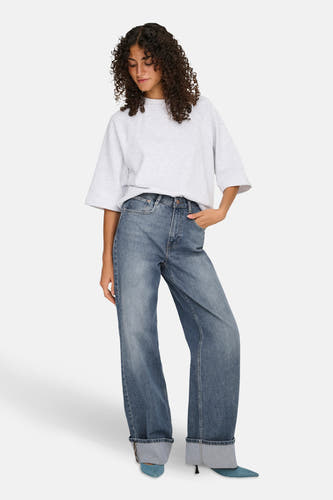 Jean bleu marine large de HOPE, associé à une chemise grise et des baskets bleues.