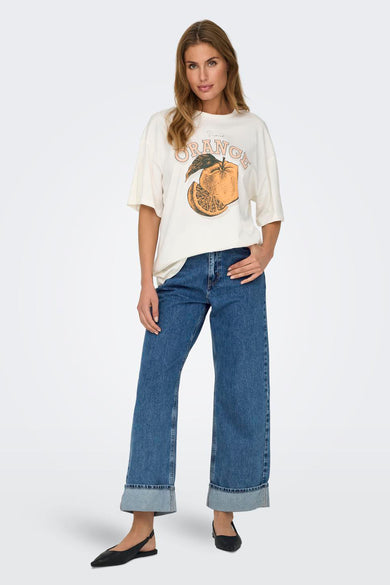 Jean denim bleu large d'ONLY, avec des poches surmontées et porté par un modèle avec un T-shirt et des chaussures plates.