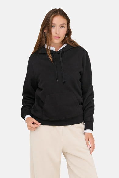 Pull-over noir avec capuche ONLY, associé à une blouse blanche et à un pantalon de jogging crème.