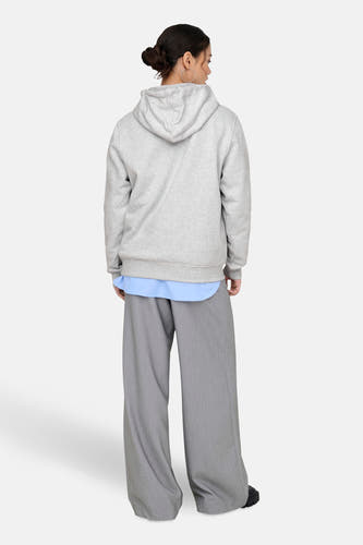 Pull-over gris avec capuche ONLY, associé à un pantalon gris large et une chemise bleue.
