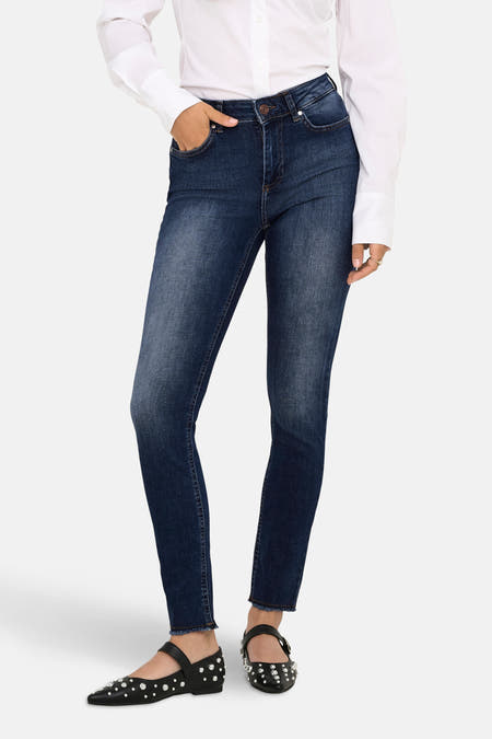 Jean skinny en denim bleu marine de ONLY, avec une blouse blanche et des chaussures noires à strass.