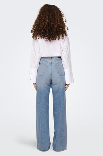 Jean large en denim bleu de ONLY, avec des jambes larges et une blouse blanche.