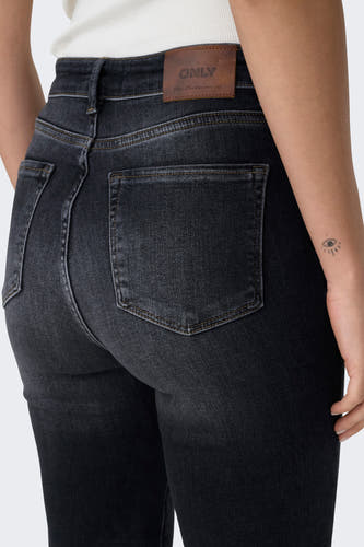 Jean mom noir de ONLY, avec une patch en cuir sur la ceinture et une petite tatouage sur le bras.