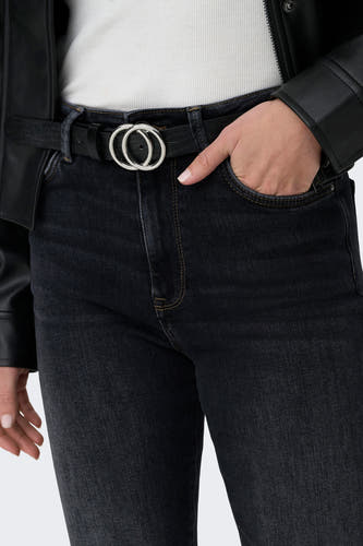 Jean mom noir de ONLY, avec des boucles d'oreilles couleur argent et une main dans la poche.