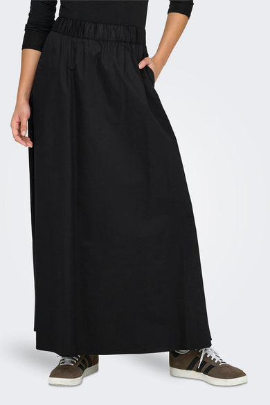 Longue jupe noire ONLY, avec une ceinture élastique et une poche, associée à des baskets marrons.
