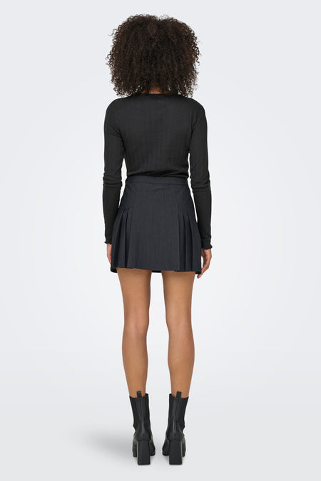 Jupe grise courte d'ONLY, avec des plis et associée à un t-shirt noir à manches longues et à des bottes noires.