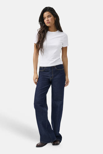 Jean ample bleu foncé ONLY® avec surpiqûres contrastées, porté par un mannequin avec un t-shirt blanc et des chaussures marron.