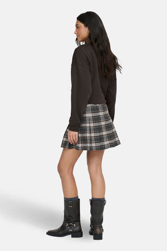 Jupe courte multicolore d'ONLY avec un motif à carreaux, associée à une chemise brune et des bottes noires.