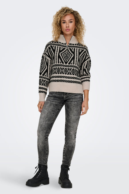 Ecru rolkraag trui van ONLY, met een zwart geometrisch patroon en grijze jeans en zwarte laarzen.