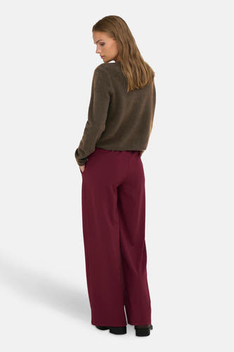 Veste brune de JDY, vue de derrière, avec un pantalon large rouge bordeaux et des cheveux bruns.
