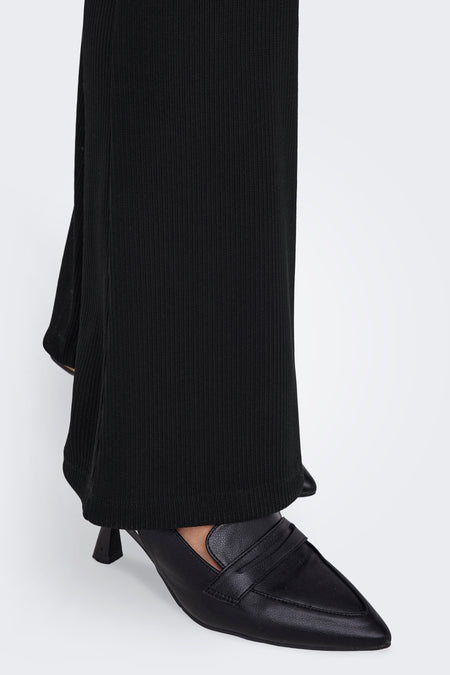Pantalon noir de ONLY, avec structure en côtes et basques tombantes, associé à des escarpins noirs en cuir à bouts pointus.