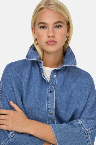 T-shirt en denim bleu de ONLY, avec une col montant et des manches longues, bras croisés.