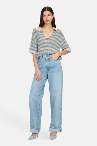 Polo bleu marine à manches courtes de JDY, avec des rayures beige associées à des jeans larges et des escarpins bleus.