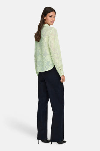 Chemise verte à manches longues de JDY, avec une texture florale, portée avec un jean foncé et des talons.