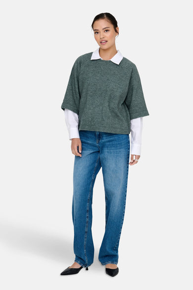 T-shirt vert avec col rond de ONLY, porté sur une chemise blanche et associé à des jeans bleus et des chaussures noires.