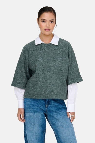 T-shirt vert avec col rond de ONLY, porté sur un chemisier blanc et un pantalon de cuir bleu.