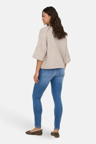 Pull beige à col rond ONLY avec des manches larges, associé à des jeans skinny bleus et des ballerines en cuir.