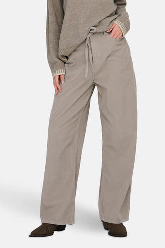 Pantalon beige de ONLY, avec cordon et larges pinces, associé à une chemise marron et des bottines en cuir de mouton.