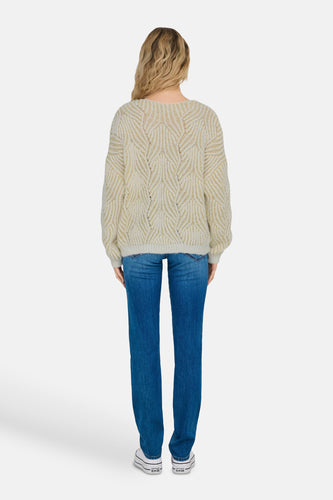 Vrouw van achteren in trui, jeans en Converse schoenen.