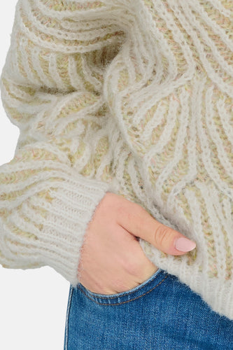 Beige kabeltrui met blauwe jeans.