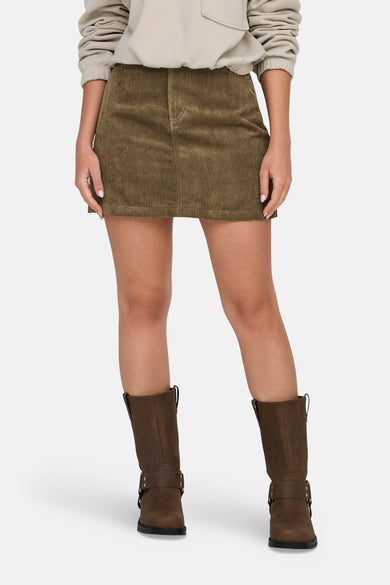 Jupe courte brune de JDY, avec une texture en velours côtelé et des poches visibles sur le dos, associée à un pull et des bottes.