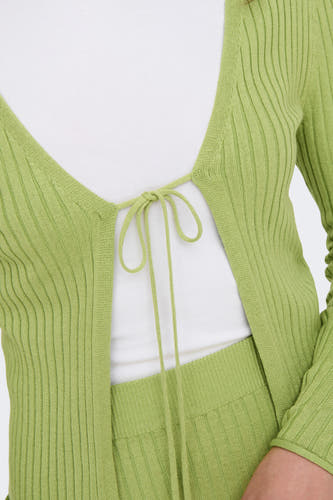 Gilet vert de ONLY, tricoté avec un détail de boutons à l'avant, porté sur une chemise blanche.