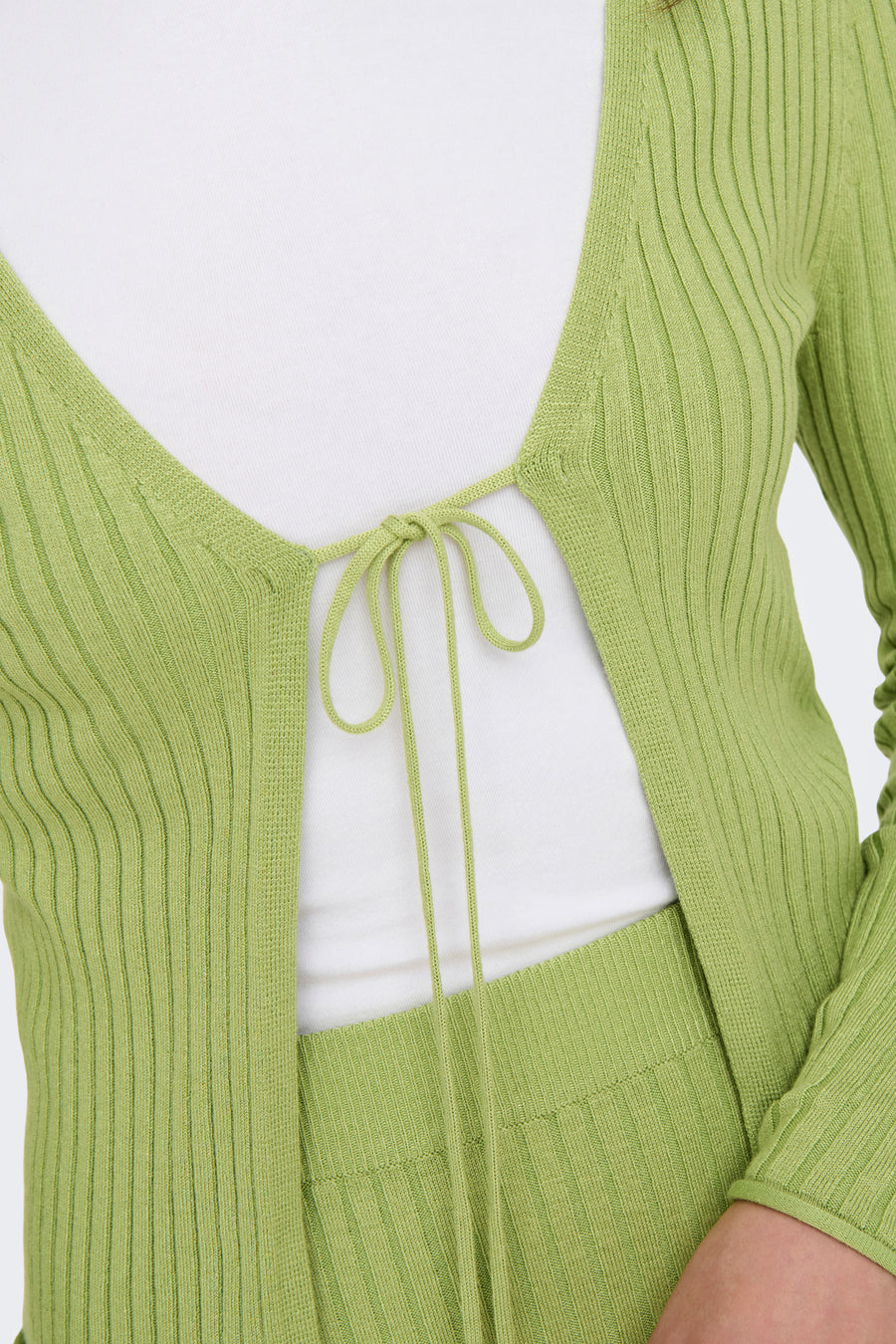 Gilet vert de ONLY, tricoté avec un détail de boutons à l'avant, porté sur une chemise blanche.