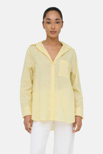 Chemise jaune à manches longues de ONLY®, portée avec un pantalon blanc et des chaussures noires.