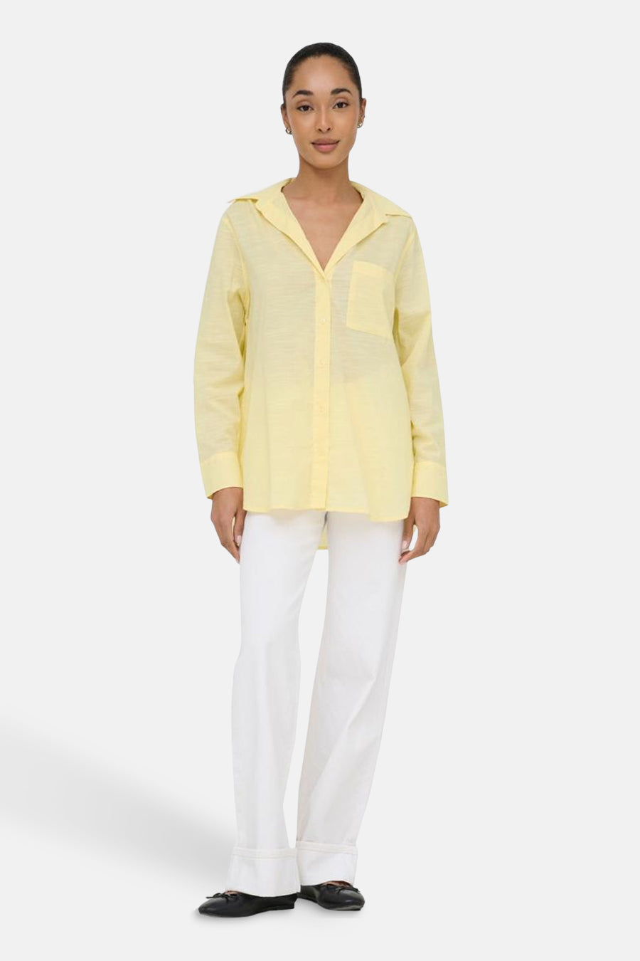 Geel hemd met lange mouwen van ONLY®, gedragen met een witte broek en zwarte schoenen.