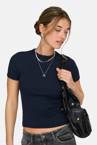 T-shirt bleu à manches courtes de ONLY, avec structure côtelée et porté avec un jean gris, des chaînes argentées et un sac noir.