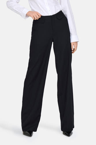 Pantalon de costume bleu ONLY, avec une rayure blanche, associé à un chemisier blanc et des escarpins noirs.