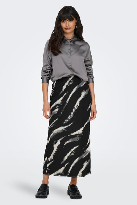 Jupe grise d'ONLY, avec un motif à rayures noires et blanches, associée à une blouse de soie grise et des chaussures noires.