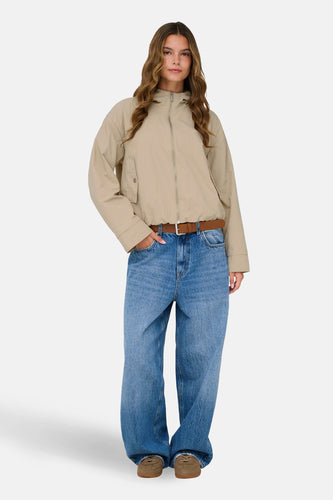 Beige korte jas van ONLY, gedragen met een bruine riem en wijde jeans.
