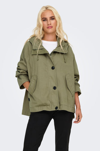 Vrouw draagt kaki jas met zwarte broek.
