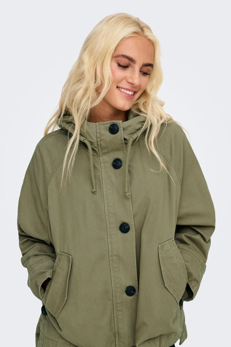 Blonde vrouw met een groene jas met zakken.