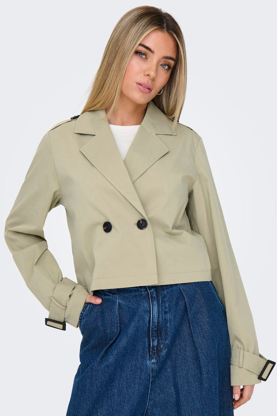 Vrouw met beige trenchcoat en blauwe jeans.