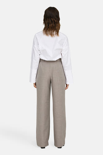 Pantalon de costume beige ONLY, avec des poches larges et un aspect soigné, associé à une chemise blanche.